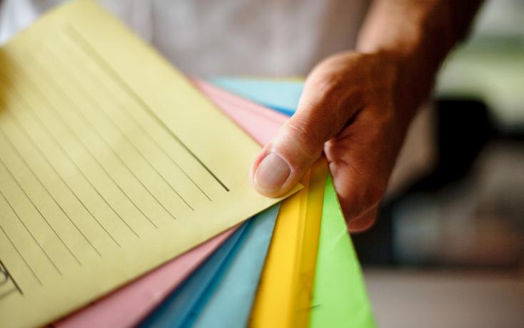 Hand hält Mäppchen in verschiedenen Farben